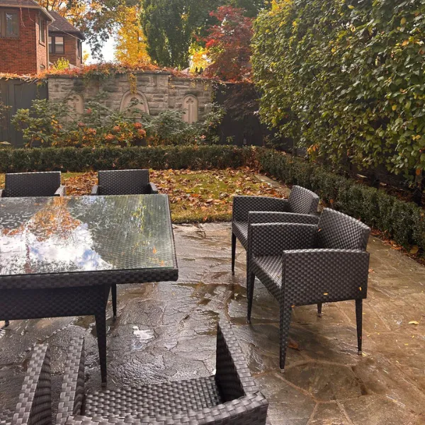 A freshly cleaned backyard patio with a reflective table and outdoor seating surrounded by fall leaves.