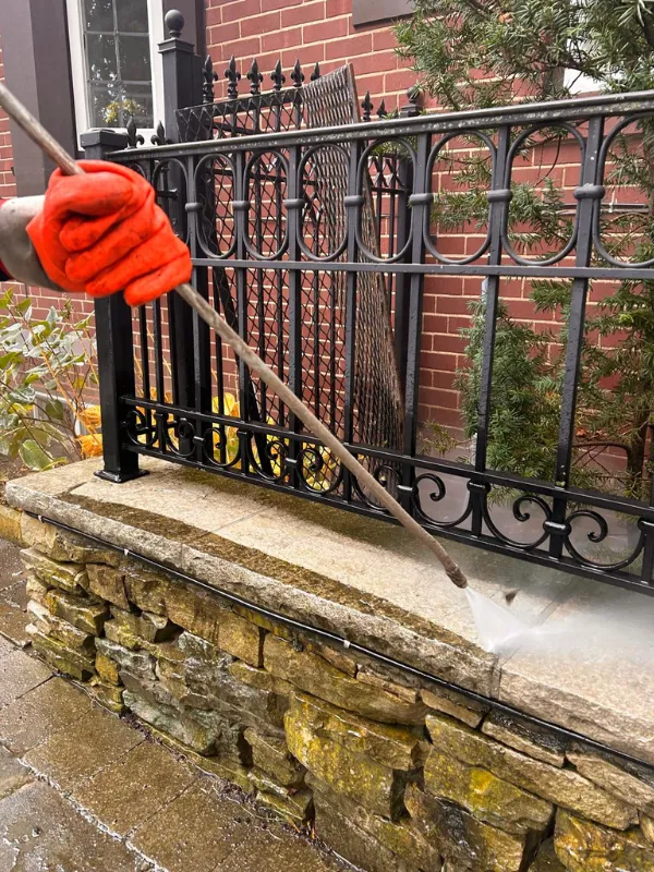 A professional pressure washing technician cleaning a stone surface with hot water, removing dirt, grime, and moss without damaging the material.